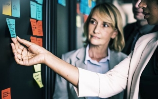 Two women review sticky notes on board