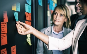 two women review sticky notes on board